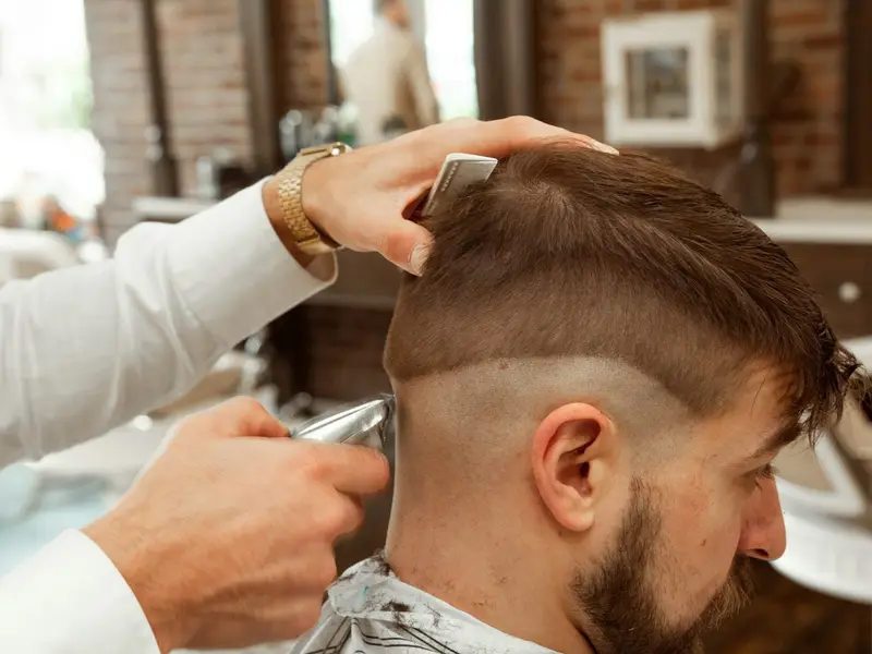 Barbeiro fazendo corte degradê com máquina